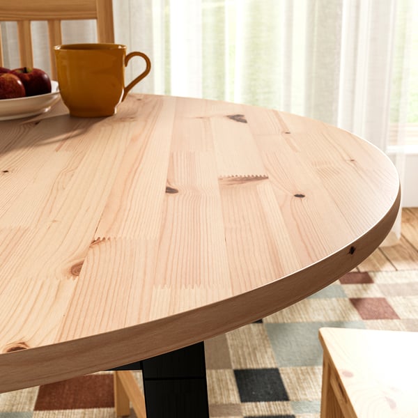 Wooden table with grain texture, apples, mug on balcony with chairs and curtains.