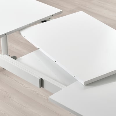 White extendable dining table with hidden leaf, shown in modern room.