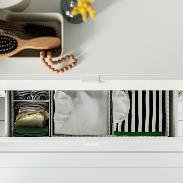 A drawer organiser with three compartments holding folded clothes and headbands, showcasing efficient storage and organisation.