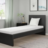 Modern bedroom with ÅBYGDA white mattress on black bed frame, minimalist decor, plant, lamp, and rug.