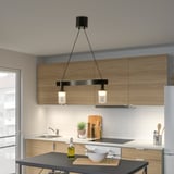 Modern kitchen with ACKJA pendant lamp over black dining table, illuminating space with warm light.