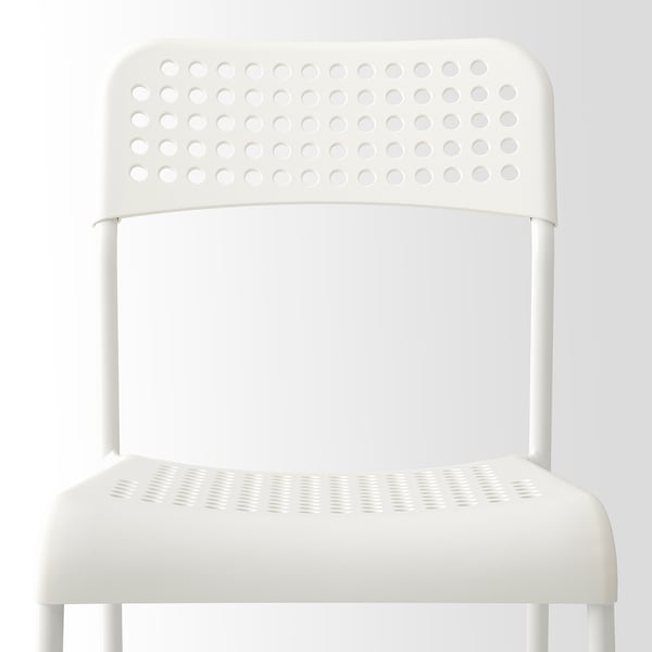 Modern stackable chair with perforated seat and backrest, sturdy legs, ideal for easy storage.