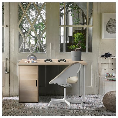 Wood desk, modern chair, patterned floor, large window, plants, art, storage. Or modern desk setup with plants, art, and storage.