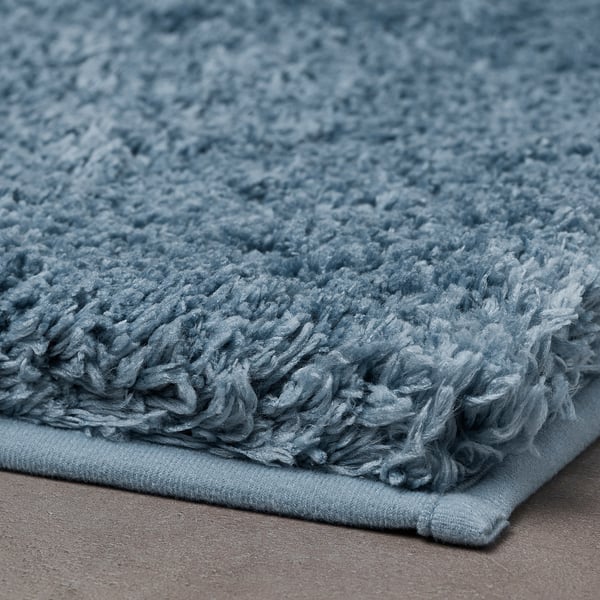 A plush, blue bath mat with a soft, textured surface and non-slip backing.