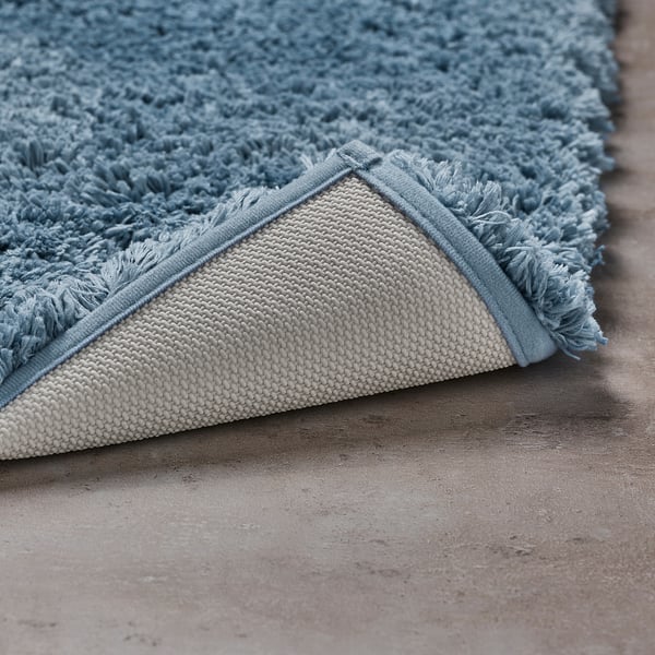 A close-up of a blue ALMTJÄRN bath mats soft, plush surface and non-slip latex backing, highlighting its texture and secure grip.