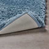 A close-up of a blue ALMTJÄRN bath mats soft, plush surface and non-slip latex backing, highlighting its texture and secure grip.