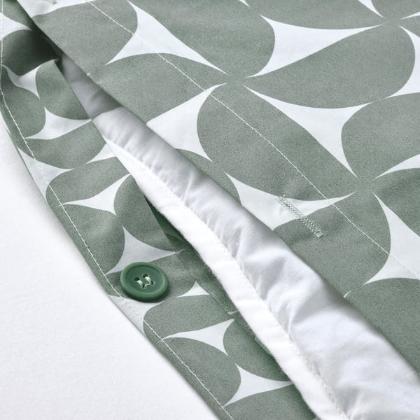Green button closure on gray patterned duvet cover.