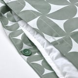 Green button closure on gray patterned duvet cover.