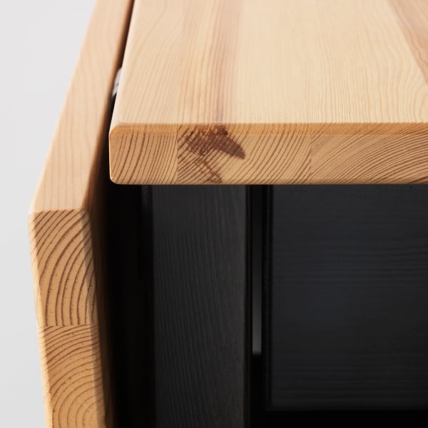 Close-up of ARKELSTORP table edge, light wood top, dark base, showing craftsmanship and quality.