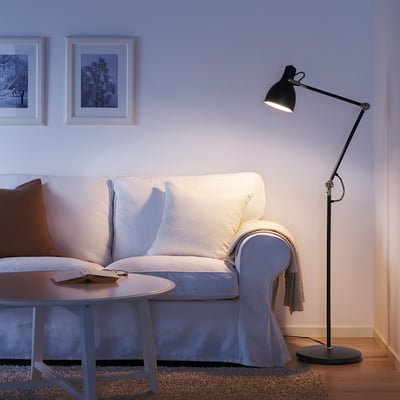 Cozy living room with white sofa, brown pillow, wooden side table, and black adjustable floor lamp.