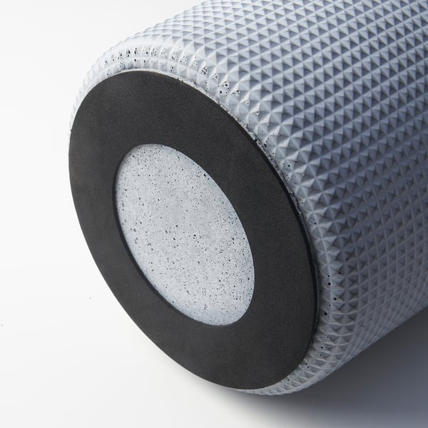 Cylindrical concrete planter with textured surface and felt pads at base for stability.