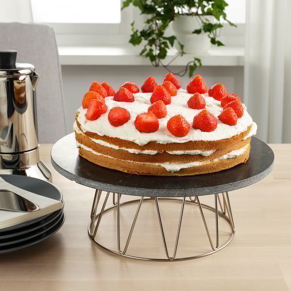 Strawberry-topped cake on rotating stand.