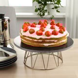 Strawberry-topped cake on rotating stand.