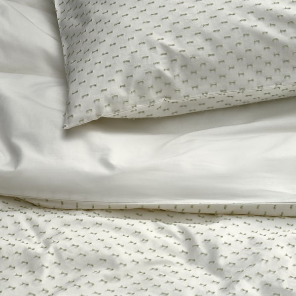Crisp white bed set with textured green embroidery, made of soft cotton for comfort.