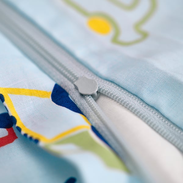 Close-up of zip on light blue childrens item. Zip partially open, revealing colourful fabric inside.