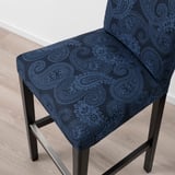 Elegant bar stool with intricate paisley pattern in deep blue. Upholstered for comfort, featuring sturdy wooden legs and supportive backrest.