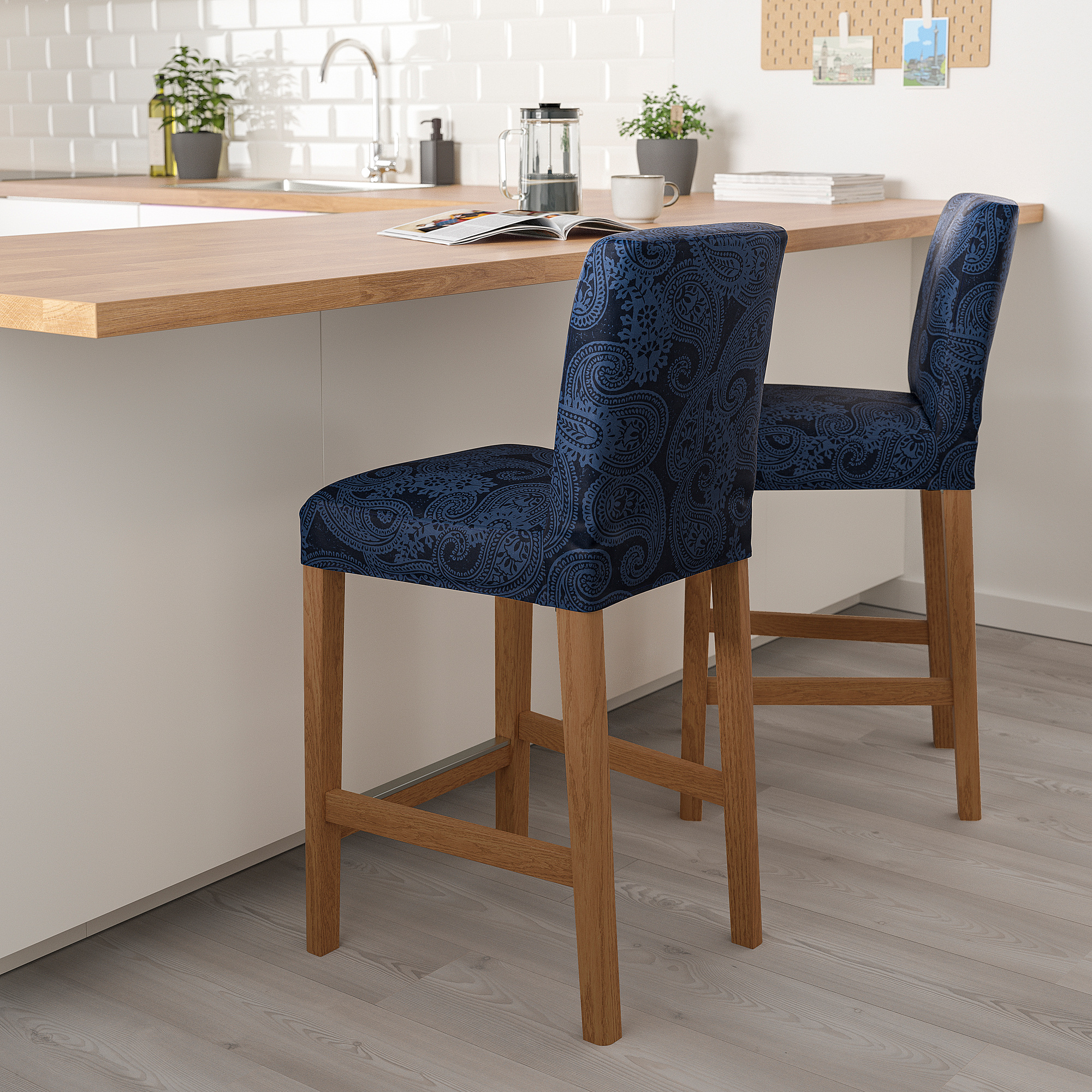 Two blue patterned bar stools at kitchen island with coffee maker and plants.