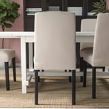 Modern dining setup with upholstered chairs around a white table. Chairs have beige covers and black legs, offering comfort and style.