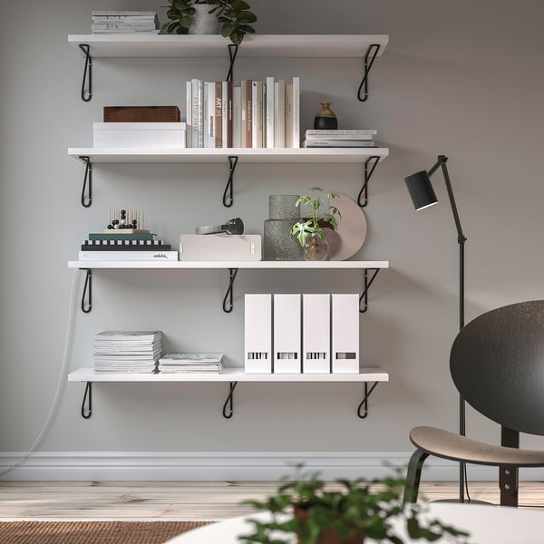 White wall shelf with black brackets holds books & decor, sleek & modern.