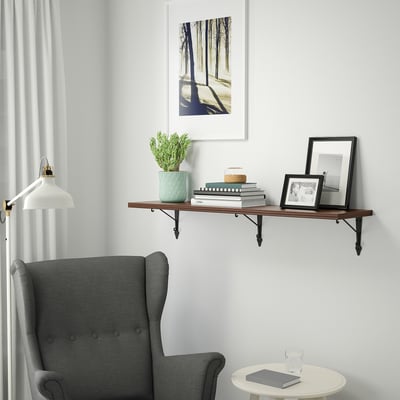 Cosy reading nook with armchair, side table, and wall shelf with books and decor.