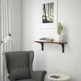 Grey nook: BERGSHULT shelf with books & plant, grey armchair, side table, forest print.