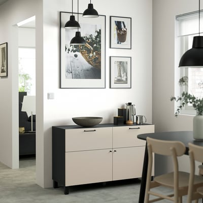 A room with a black and white BESTÅ sideboard, pendant lights, light wood chairs, and minimal decor.