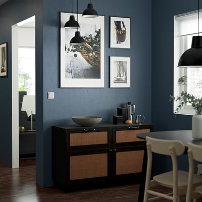 Dark blue wall with BESTÅ sideboard, white chairs, hanging lights, and framed art. Furniture is mid-sized.