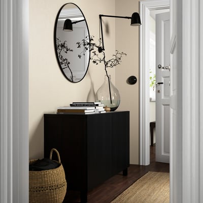 Modern entryway with BESTÅ sideboard, plants, books, mirror, basket, open door.