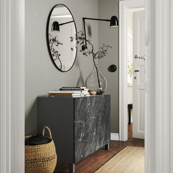 Modern hallway featuring BESTÅ storage unit in black with marble top, basket, and round mirror.