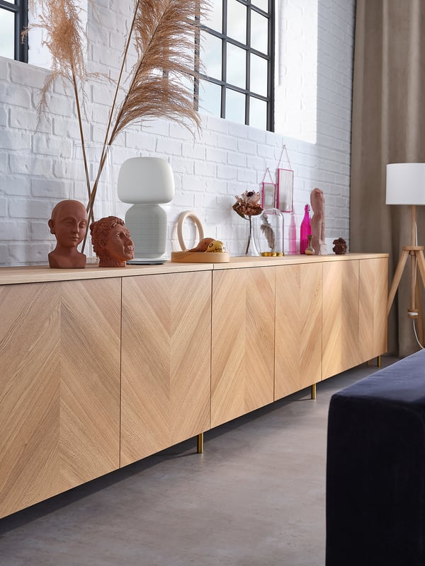 Minimalist room with white brick walls, a long light wood BESTÅ sideboard, various decor items, and large windows.