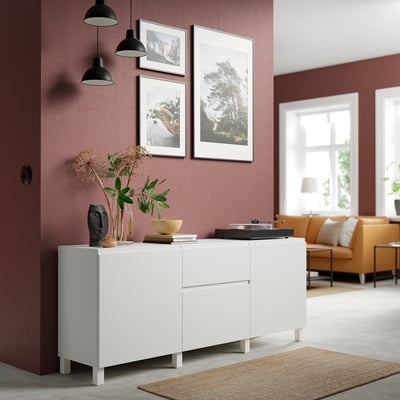 White BESTÅ sideboard with decorations, pictures, and yellow sofa beside burgundy walls.
