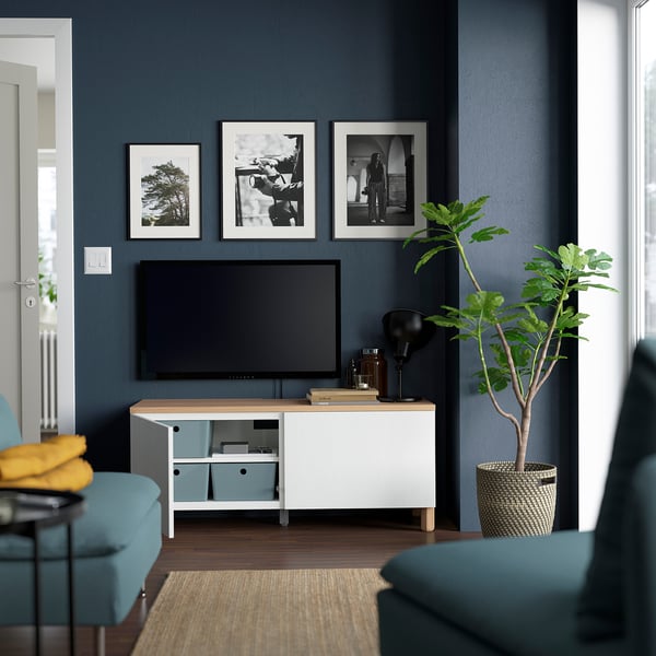 Modern living room with dark walls, tv on BESTÅ, blue chairs.