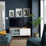 Modern living room with dark walls, tv on BESTÅ, blue chairs.