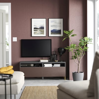 Modern living room with purple walls, white sofa, wooden tv stand, potted plant, and framed nature photos.