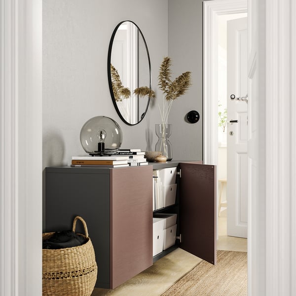 Modern entryway with BESTÅ cabinet, open shelves, mirror, plants, books, & bulb.