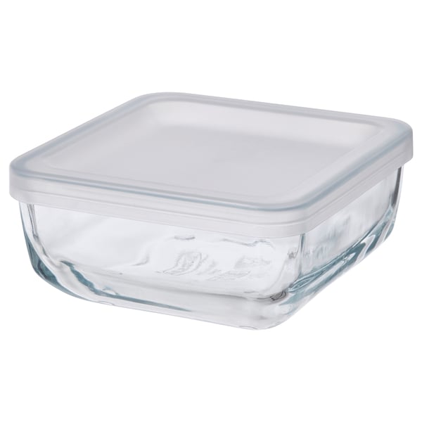 A clear glass food container with a white plastic lid. Its square-shaped and designed for storing food.