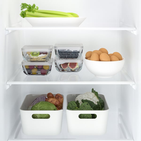 Well-organized fridge with stacked glass food containers, storing fruits and leftovers. Transparent design for easy identification and space-saving.
