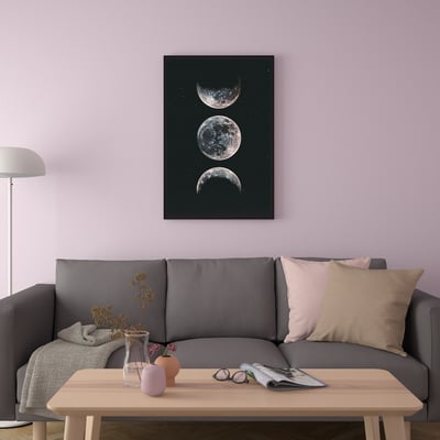 Gray sofa with cushions against purple wall, moon phase poster, coffee table with plants, magazine, singing bowl, lamp.