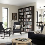 Living room with tall BILLY bookcase, dark armchairs, wood coffee table, and large window.