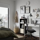 Modern home office with BILLY bookcase, desk, & bed. Geometric wallpaper & city view.