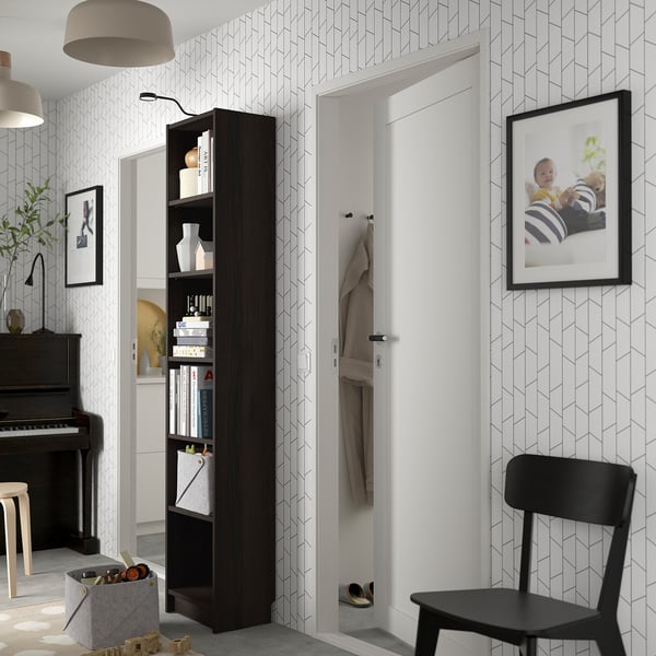 Black BILLY bookcase filled with books and vases, geometric wallpaper, piano, and chair.