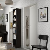 Black BILLY bookcase filled with books and vases, geometric wallpaper, piano, and chair.
