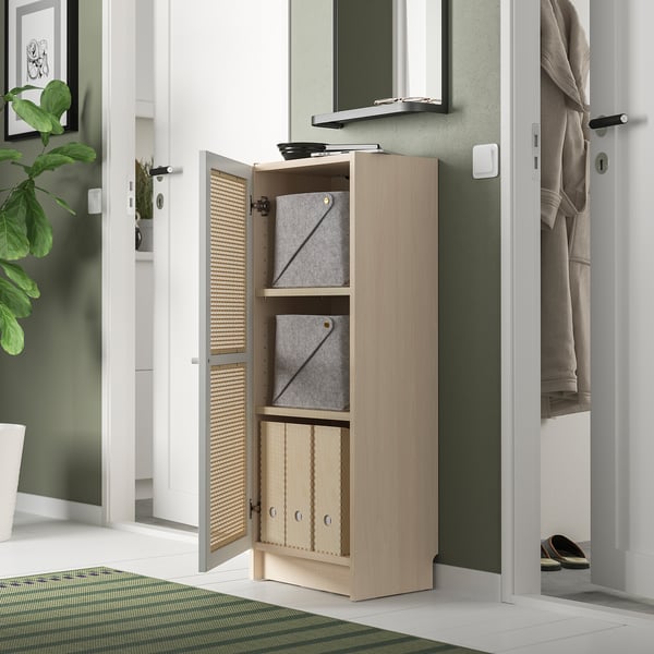 A light-colored wooden BILLY bookcase with bamboo doors, featuring gray bins and situated in a green-themed room.