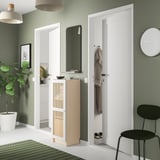 Modern hall with green walls, white doors, black chair, potted plant. BILLY bookcase with bamboo door, white and natural colors.