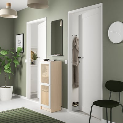 Modern hall with green walls, white doors, black chair, potted plant. BILLY bookcase with bamboo door, white and natural colors.
