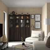 Modern living room with large BILLY bookcase. Dark wood, glass doors, white couch, black and white decor, light wood walls.