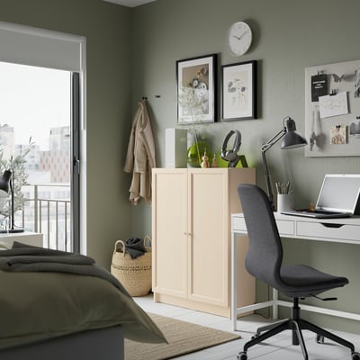 Cozy bedroom with BILLY bookcase, green wall, wooden desk, black chair, and bed with green blanket.