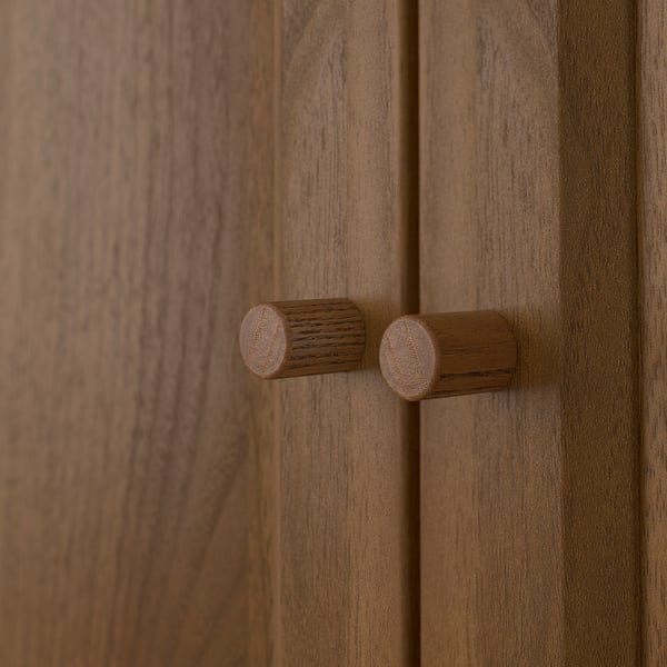 Close-up of two wooden knobs on a light brown wooden panel, smooth in texture.