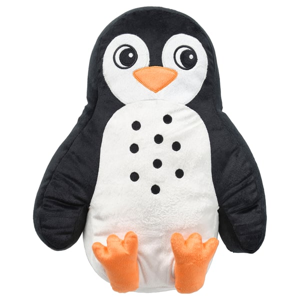 A BLÅVINGAD penguin-shaped cushion. It is black and white with orange feet and beak, filled with recycled polyester.