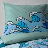 Two vibrantly patterned pillows with turquoise and blue wave designs on a mint background.